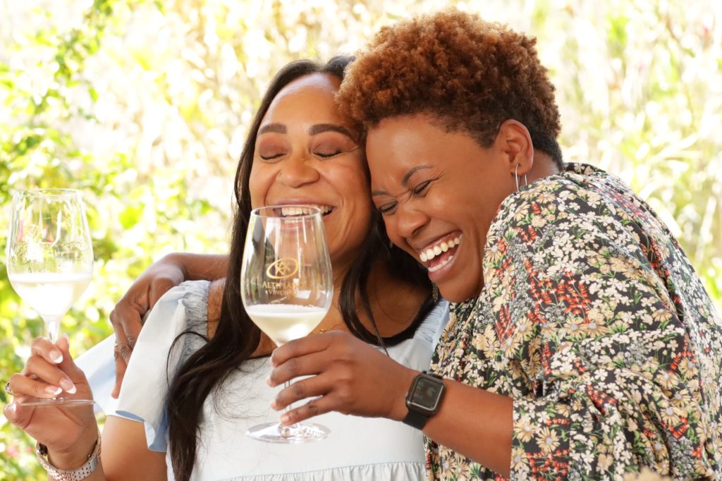 Cassandra Schaeg laughs with a woman while they sip wine